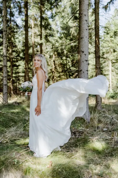 Braut Katrin mit fliegender Schleppe und Brautstrauß im Wald - Martin Schinnerl Fotografie