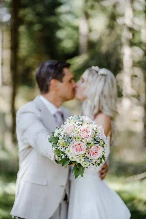 Katrin und Mario küssen sich mit Brautstrauß im Vordergrund - Martin Schinnerl Fotografie