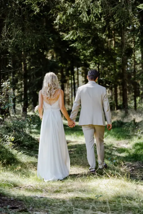 Katrin und Mario spazieren Hand in Hand durch den Wald