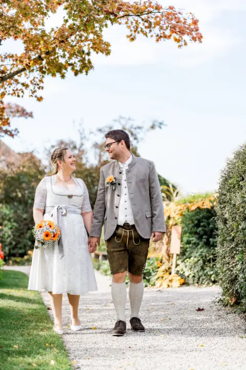 Sabrina und Markus spazieren Hand in Hand mit Brautstrauß im Literaturgarten - Martin Schinnerl Fotografie