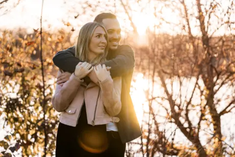 Stefan umarmt Stefanie beim Paarshooting zu herbstlicher Abendsonne an der Donau - Martin Schinnerl Fotografie