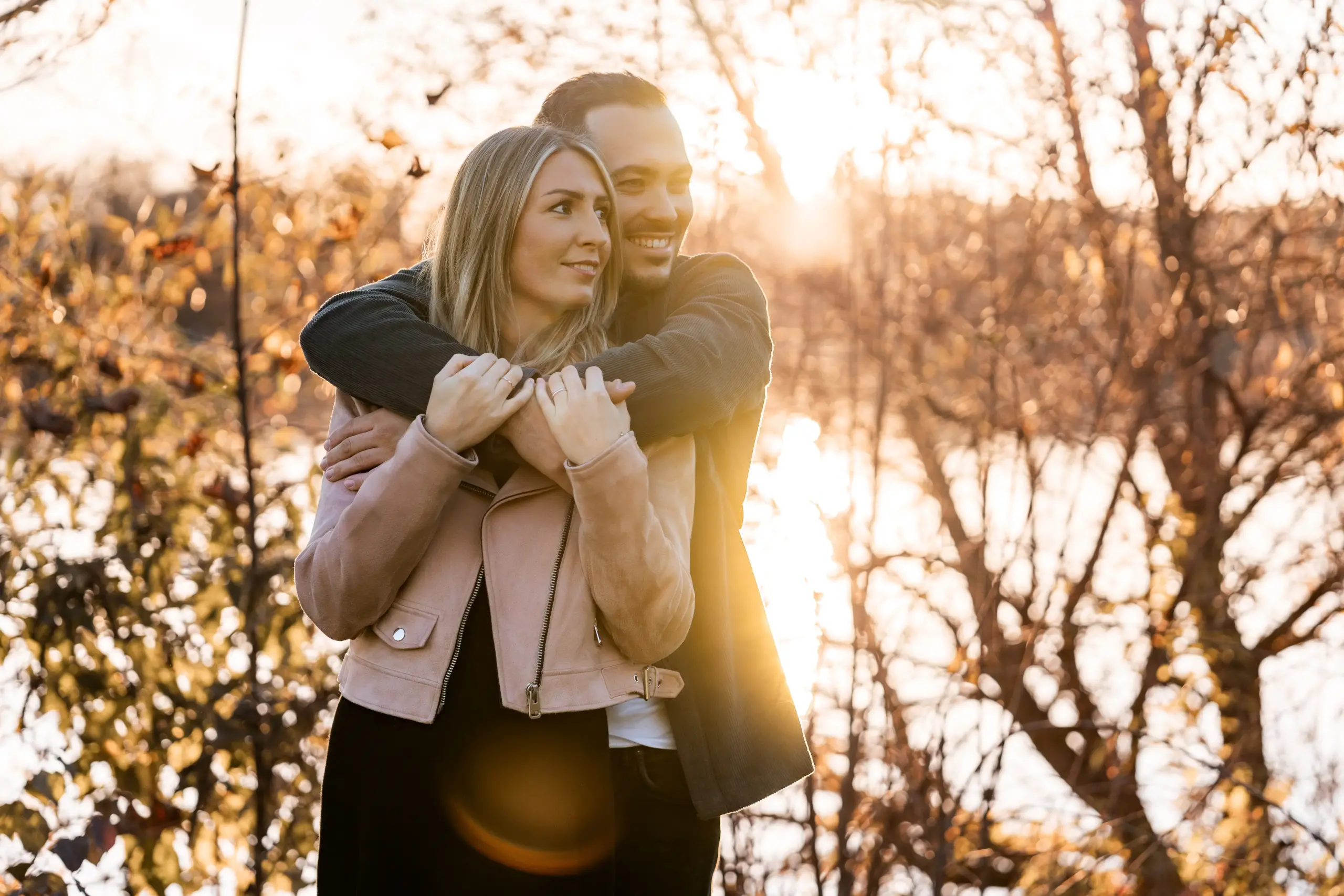 Stefan umarmt Stefanie beim Paarshooting zu herbstlicher Abendsonne an der Donau - Martin Schinnerl Fotografie