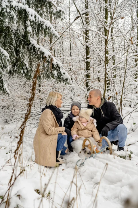 Katharina und Marcel sitzen mit ihren Kindern im Wald im Schnee - Martin Schinnerl Fotografie