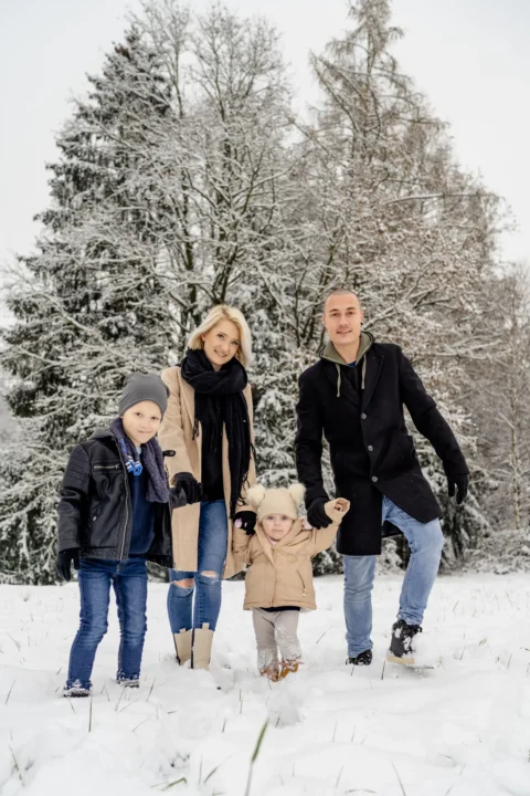 Katharina und Marcel spazieren Hand in Hand mit ihren Kindern durch den Schnee - Martin Schinnerl Fotografie
