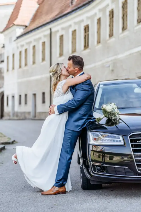 Petra und Gerhard küssen sich am Brautauto - Martin Schinnerl Fotografie
