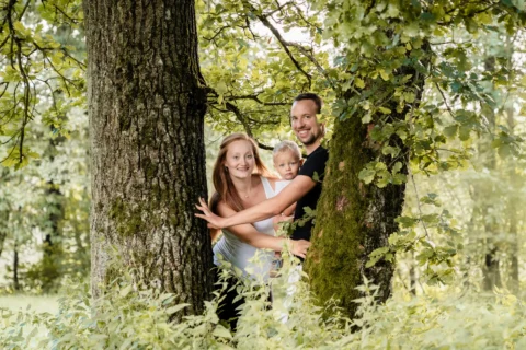 Vater, Mutter und Kind beim Familienshooting zwischen zwei Bäumen in der Natur - Martin Schinnerl Fotografie