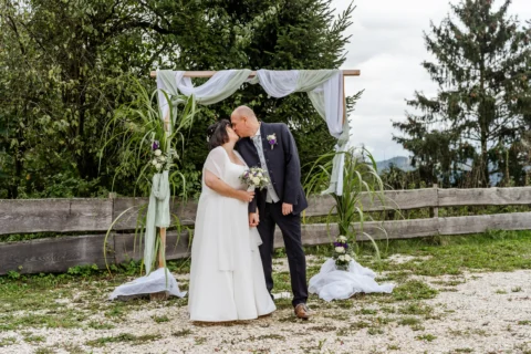 Sabine und Dietmar küssen sich unterm Fotobogen bei der Hochzeitslocation Fani-Alm im Bezirk Perg - Martin Schinnerl Fotografie