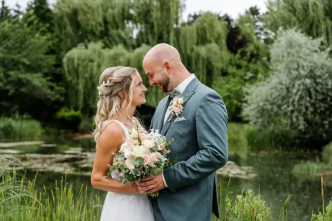 Braut und Bräutigam posieren für romantische Paarfotos am Ufer des Teichs in St. Valentin - Martin Schinnerl Fotografie
