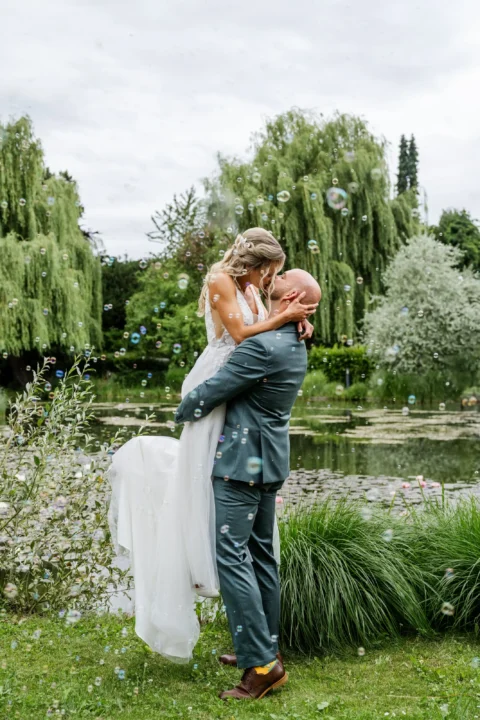 Der Bräutigam hebt seine Braut hoch und küsst sie beim Paarshooting bei der Hochzeit in St. Valentin beim Wirt am Teich - Martin Schinnerl Fotografie