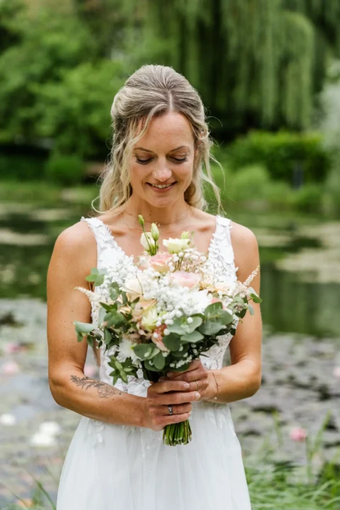Die Braut betrachtet ihren Brautstrauß beim Paarshooting in St. Valentin beim Wirt am Teich - Martin Schinnerl Fotografie