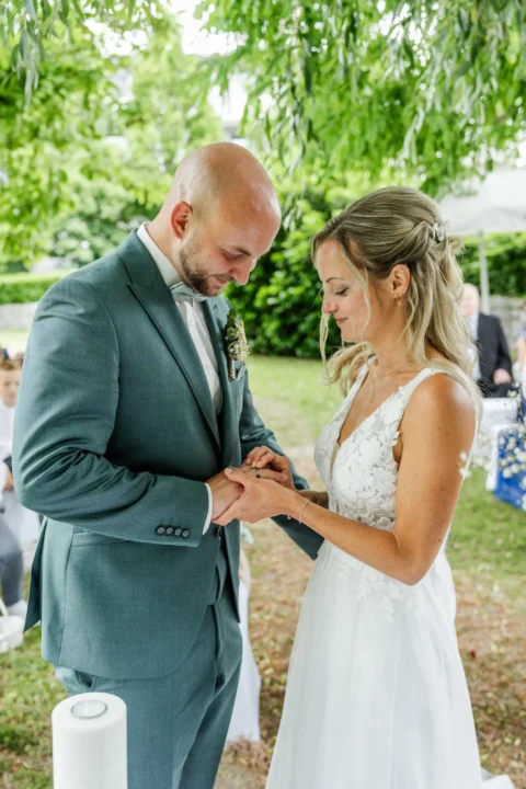 Die Braut steckt dem Bräutigam den Ring an während der Trauung in St. Valentin - Martin Schinnerl Fotografie.webp
