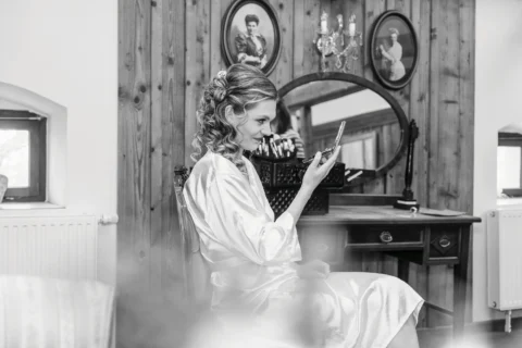 Braut schminkt sich am Spiegel während der Hochzeitsvorbereitungen im Vedahof - Martin Schinnerl Fotografie