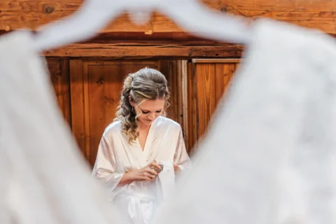 Braut sprüht Parfüm vor Hochzeitskleid während Vorbereitung - Martin Schinnerl Fotografie