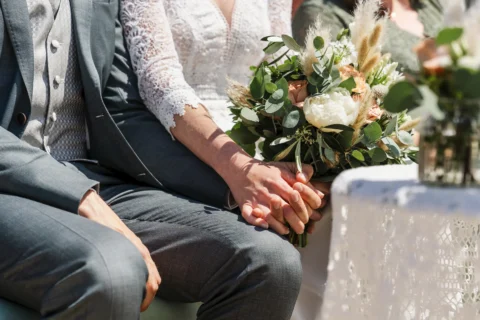 Braut und Bräutigam halten Hände während der Trauung und Brautstrauß - Martin Schinnerl Fotografie