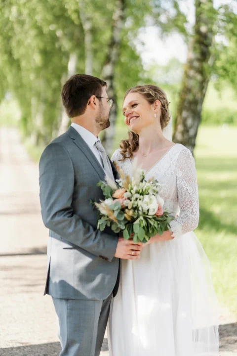 Brautpaar blickt sich verliebt an auf Allee beim Vedahof - Martin Schinnerl Fotografie