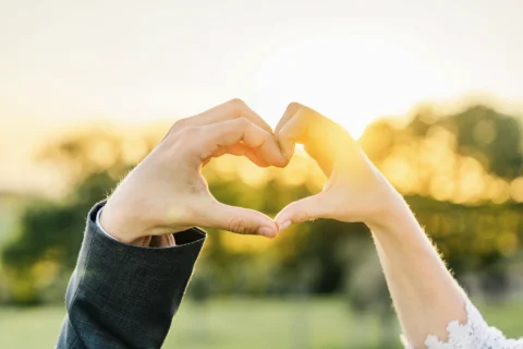 Brautpaar formt Herz mit Händen vor Sonnenuntergang - Martin Schinnerl Fotografie