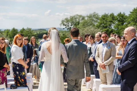 Brautpaar schreitet durch Gästereihen zur Trauung im Freien - Martin Schinnerl Fotografie