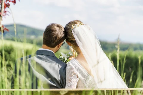 Brautpaar sitzt auf einer Bank im Garten des Vedahofs bei der Hochzeit im Mai - Martin Schinnerl Fotografie