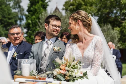 Brautpaar sitzt bei Trauung im Freien und schaut sich verliebt an - Martin Schinnerl Fotografie