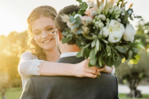 Brautpaar umarmt sich im Sonnenuntergang mit Brautstrauß - Martin Schinnerl Fotografie