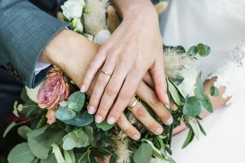 Hände mit Eheringen auf Brautstrauß bei der Hochzeit - Martin Schinnerl Fotografie